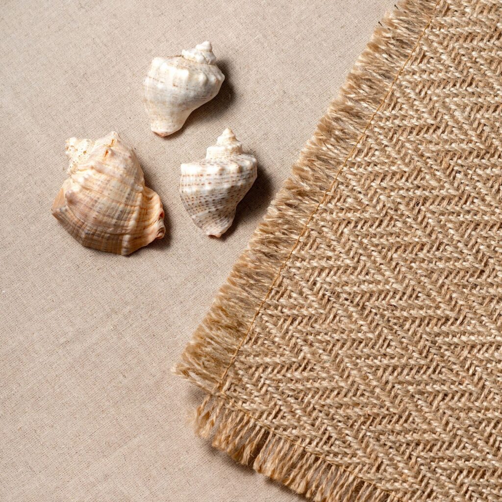 Minimal square aesthetic neutral summer vacation concept with sea shells and jute rug on a beige background, copy space